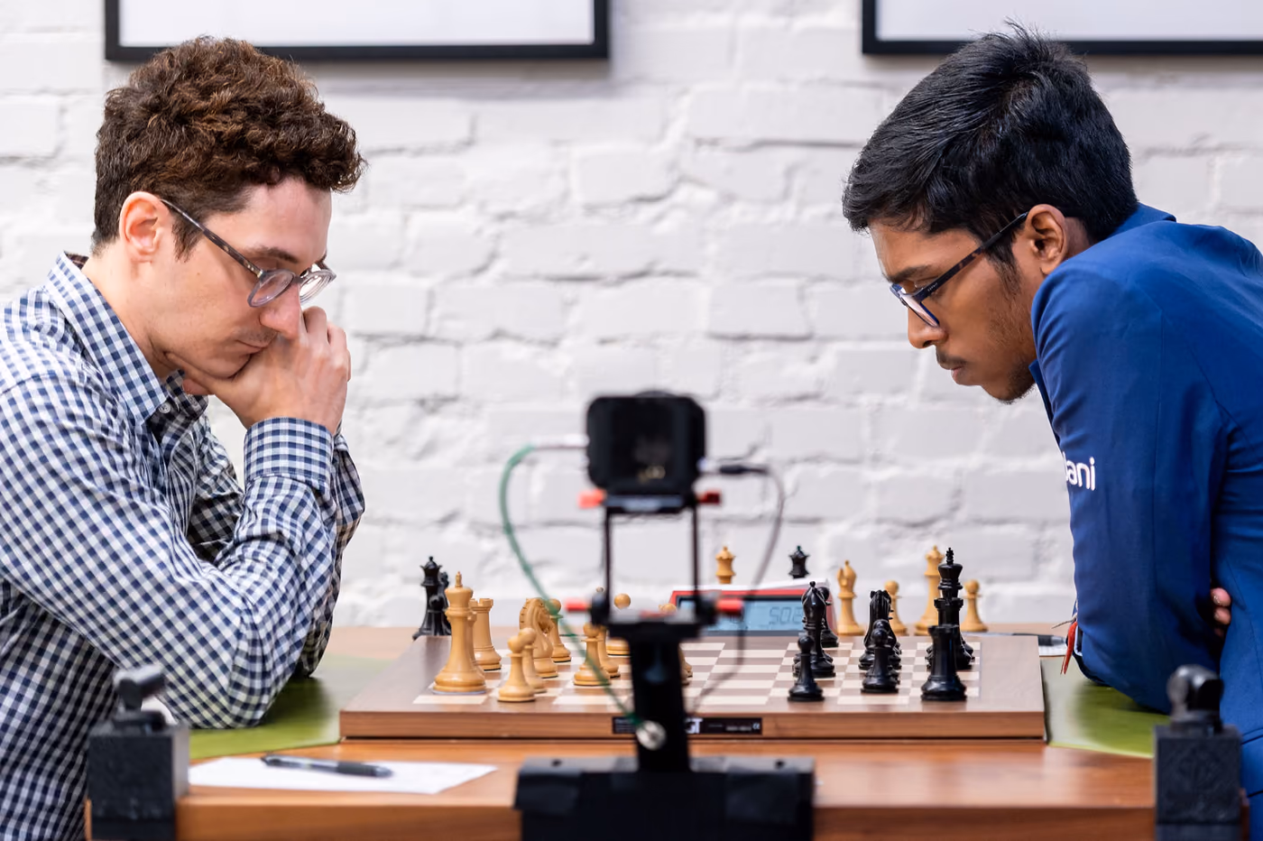 Fabiano Caruana and Rameshbabu Praggnanandhaa playing across a chessboard