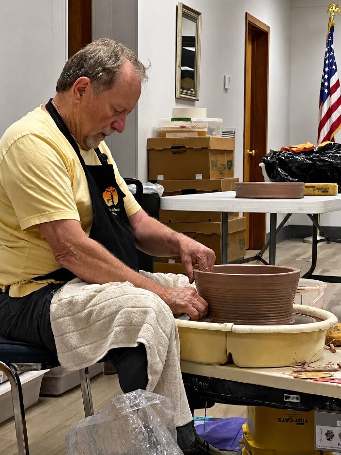 Byron Myrick shaping a slab pot on a pottery wheel.
