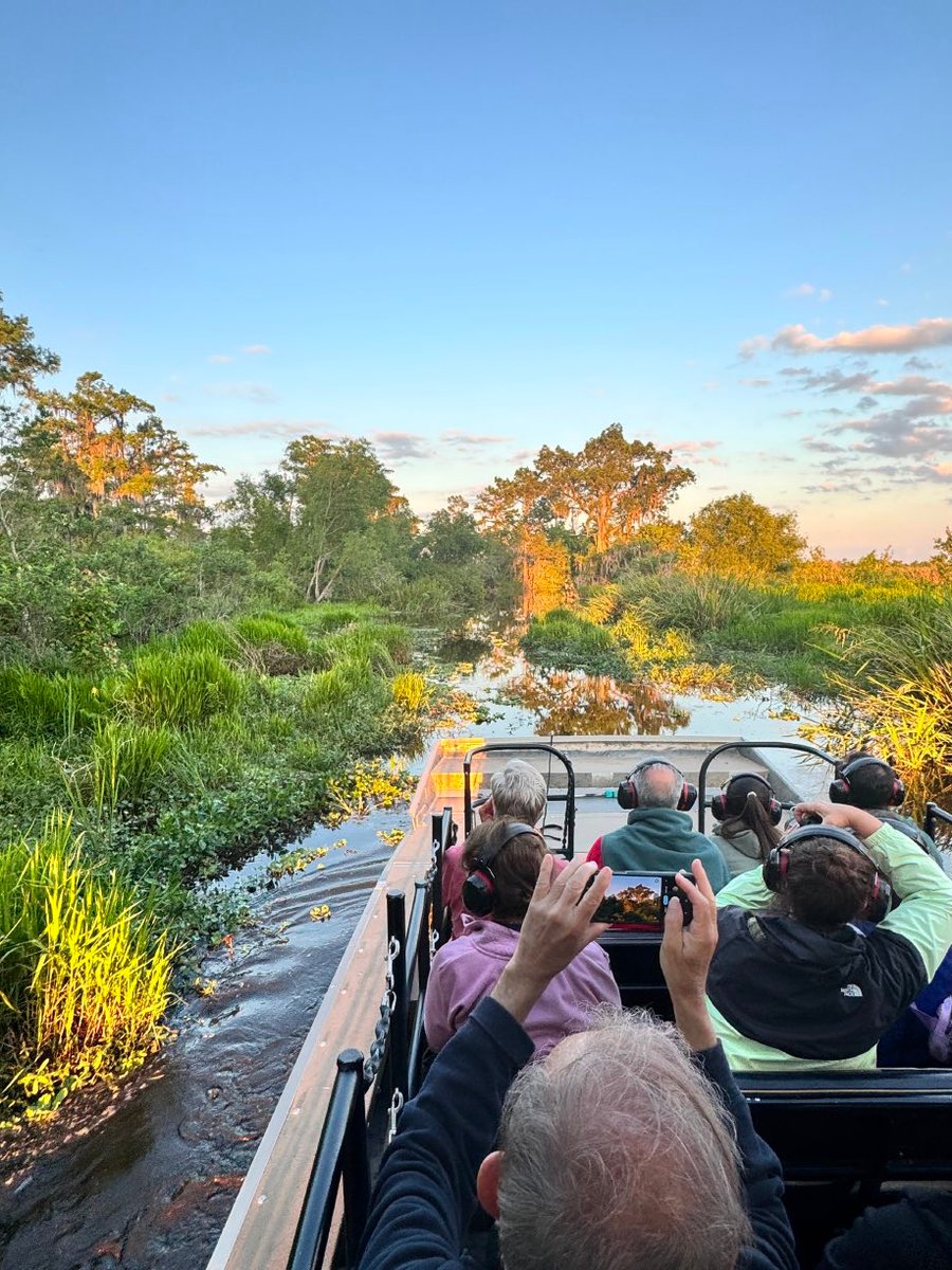 Attendees on an airboat touring the cypress swamp at sunset.